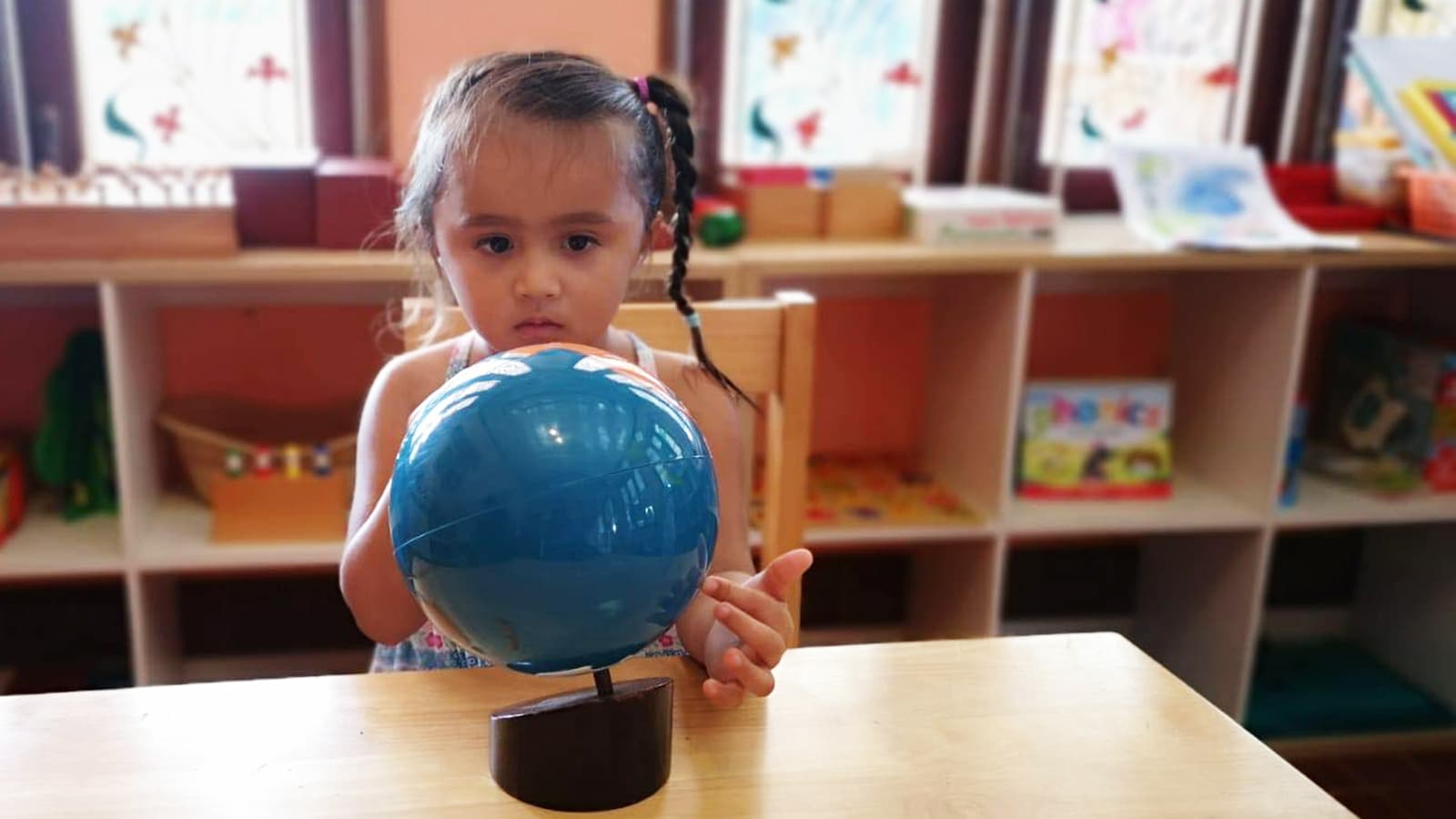 A child holding a globe at a table in the Daisy Chains classroom